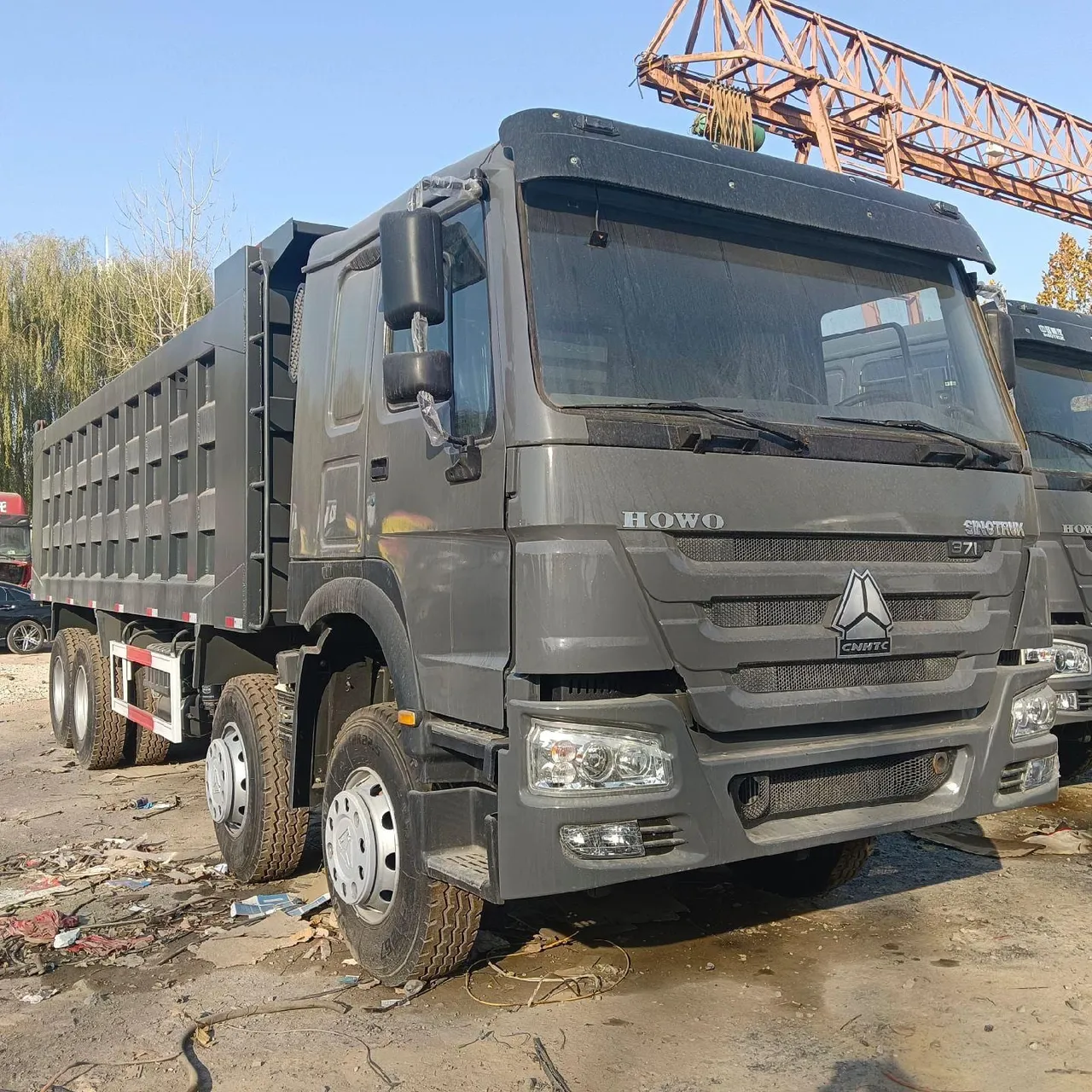 Used HOWO and SHACMAN dump lorries lined up in yard, export-ready for Africa and Middle East