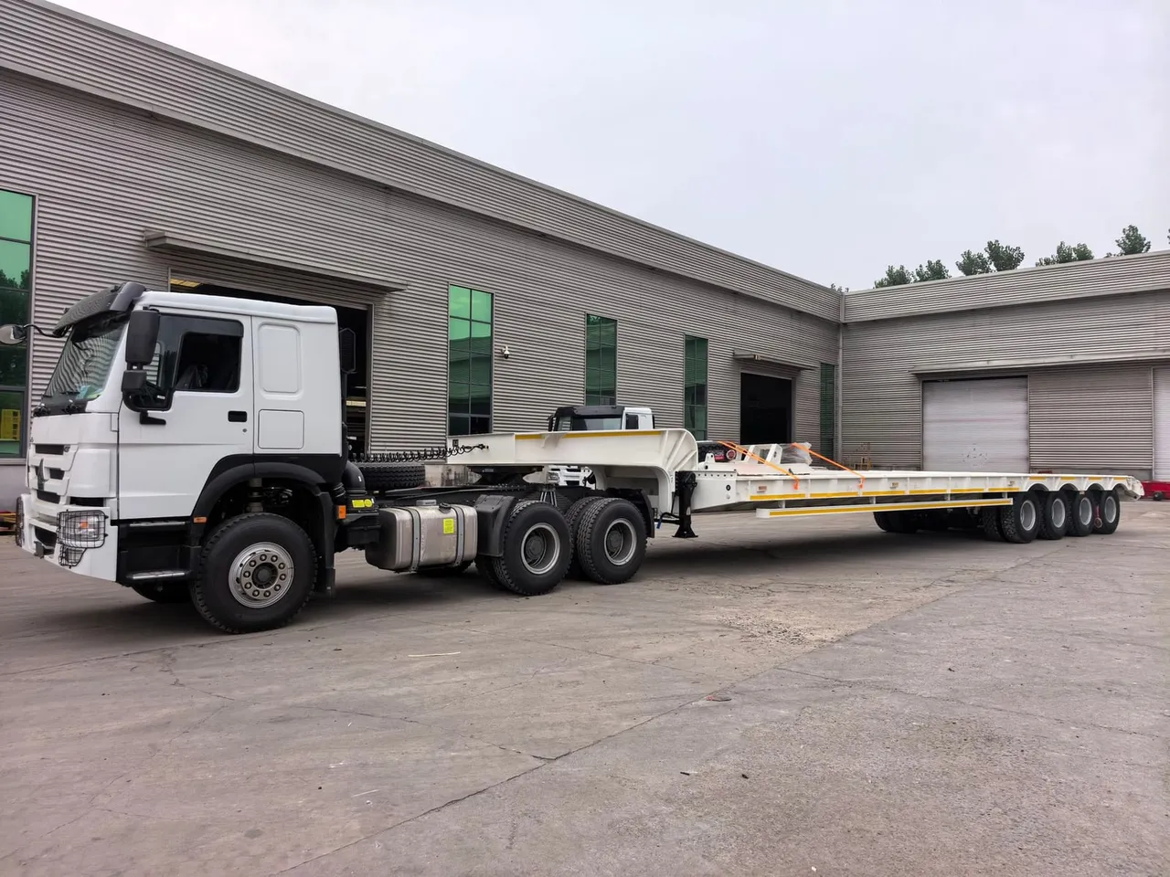 Used tri-axle flatbed semi-trailer loaded with steel pipes, ready for export