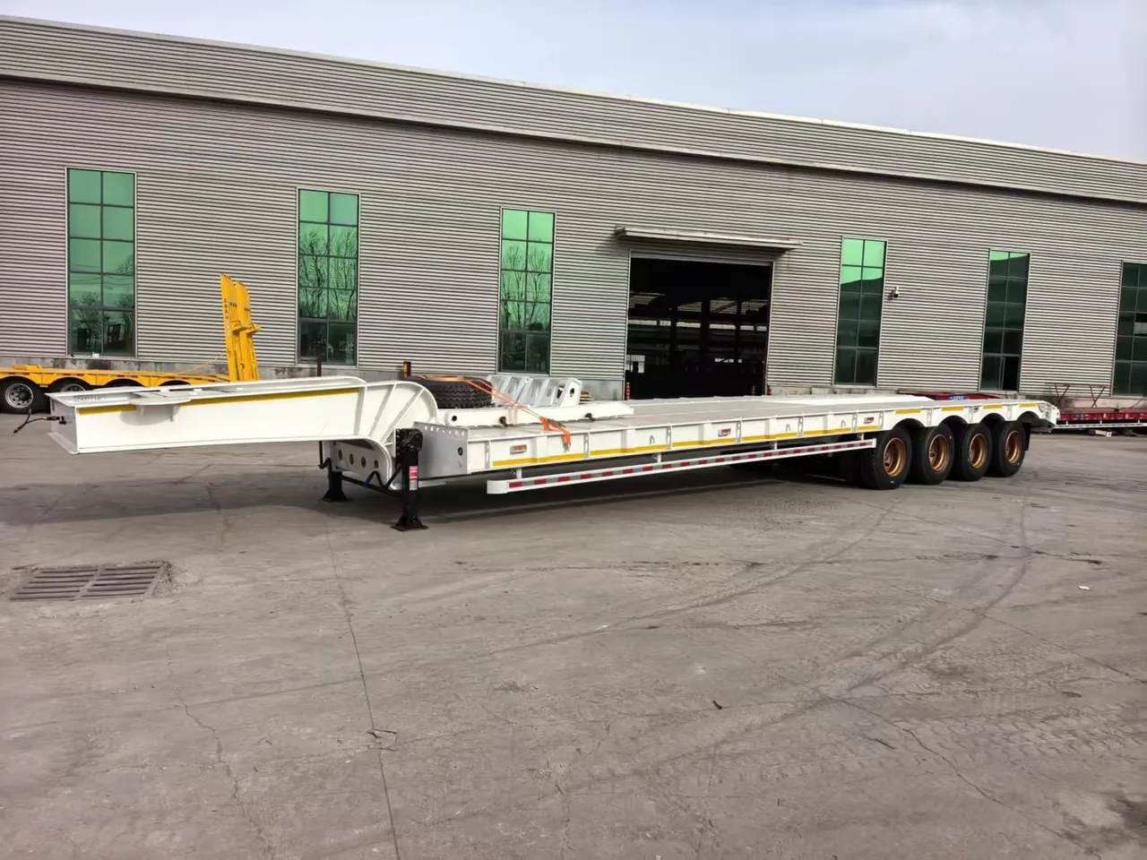 Used 3-axle flatbed semi-trailer with open steel deck ready for loading